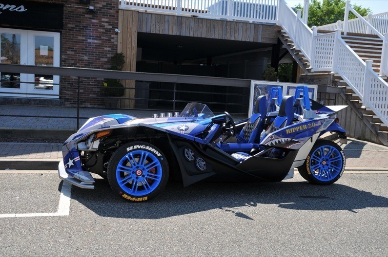 Black and blue Slingshot motorcycle with blue rims parked in front of restaurant
